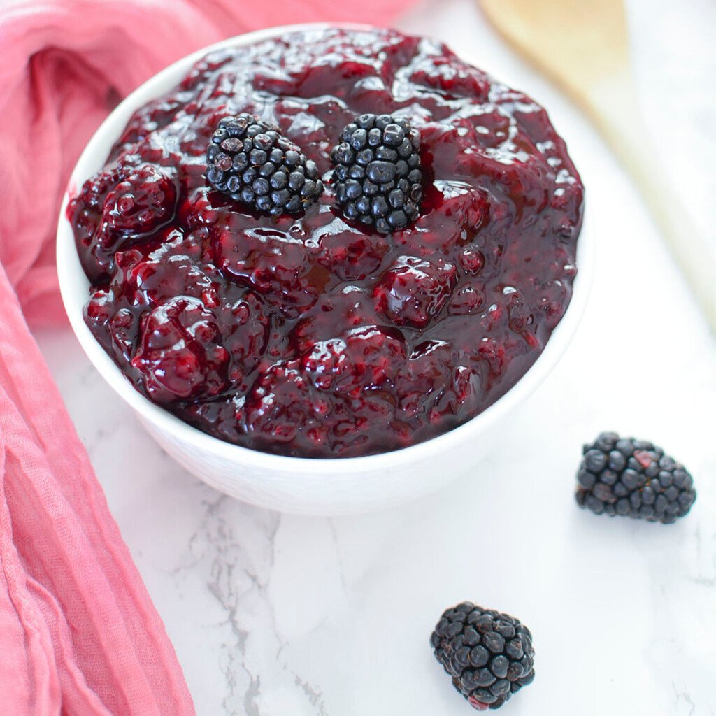 Blackberry pie filling in a white bowl, square photo.