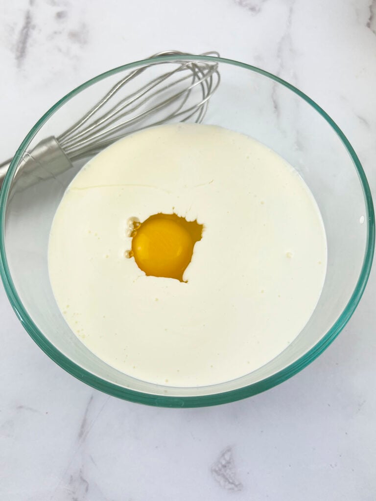 Heavy cream with an egg dropped inside, just before whisking.