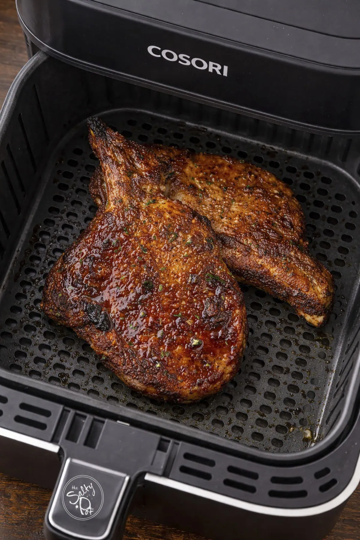 Two airfryer porkchops in the airfryer basket.