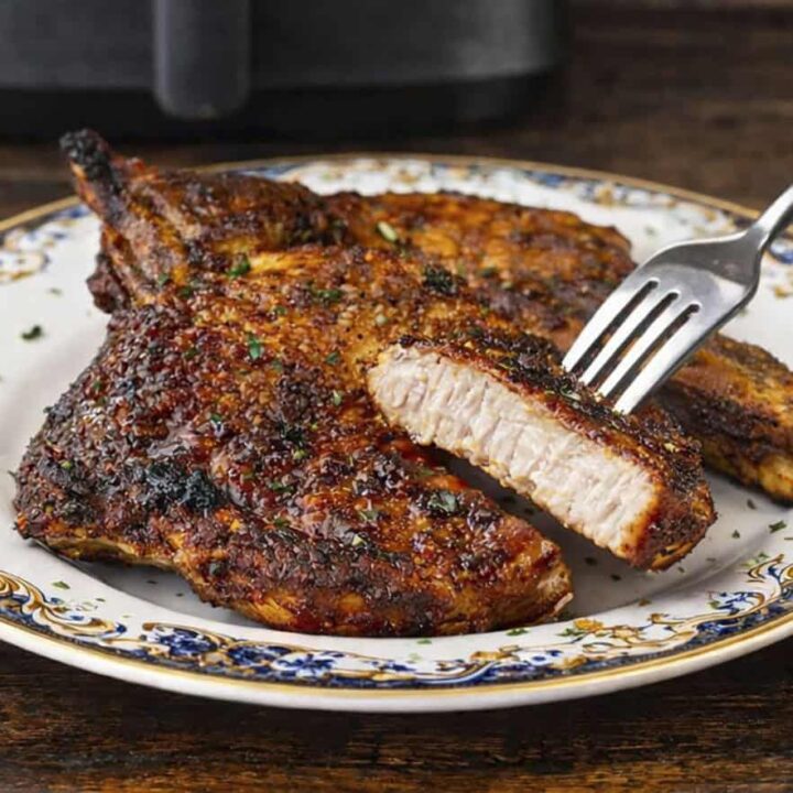 A close up photo of pork chops on a late, cooked in the air fryer.