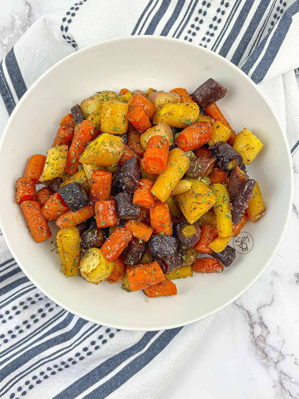 Honey ginger roasted rainbow carrots in a white bowl.