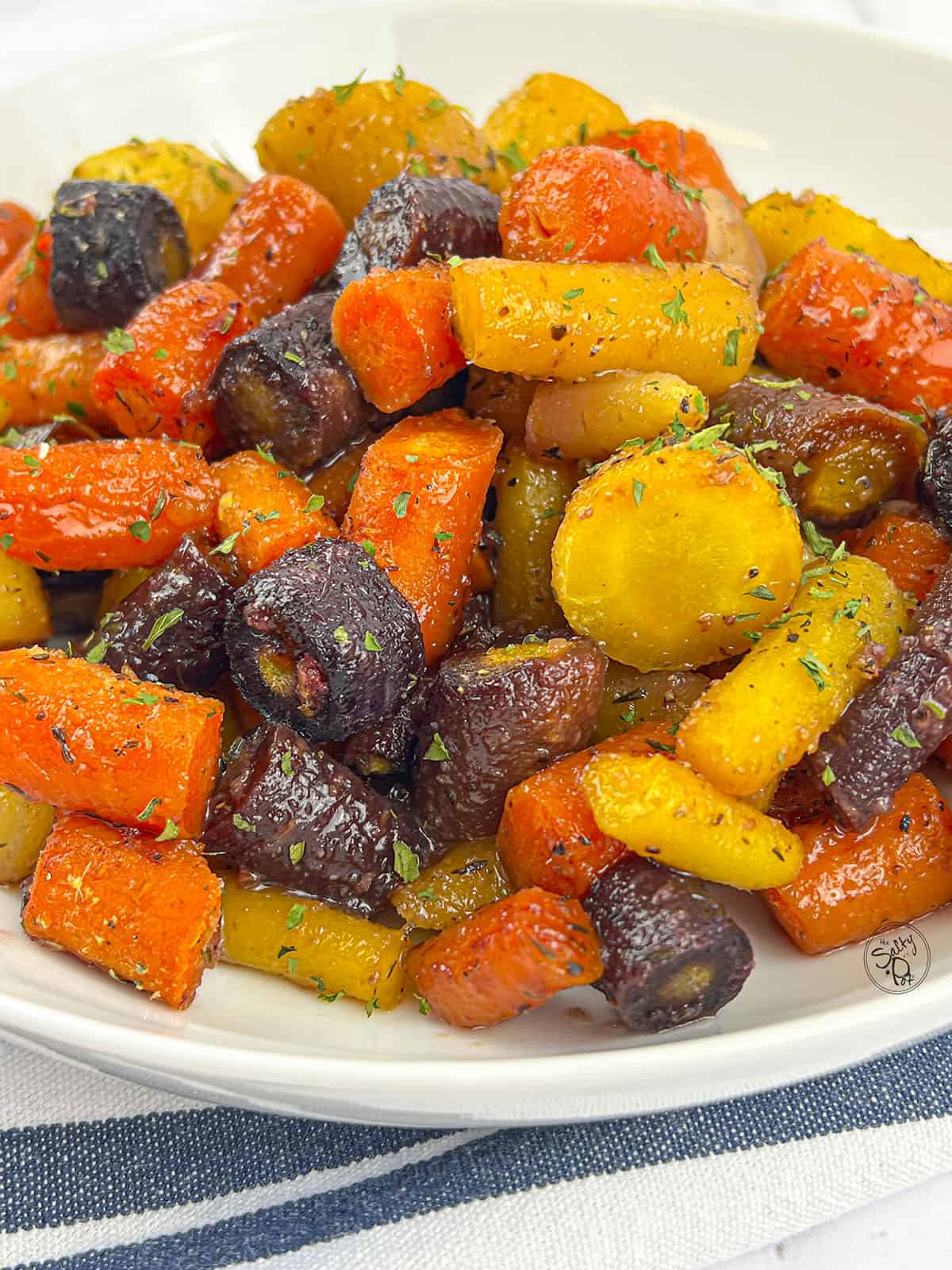 Rainbow carrot pieces that are roasted in a white dish. 