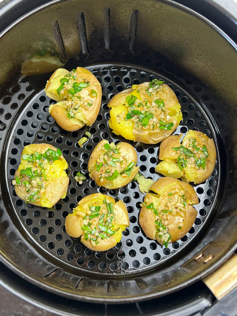 The smashed potatoes are seasoned and placed in the air fryer.