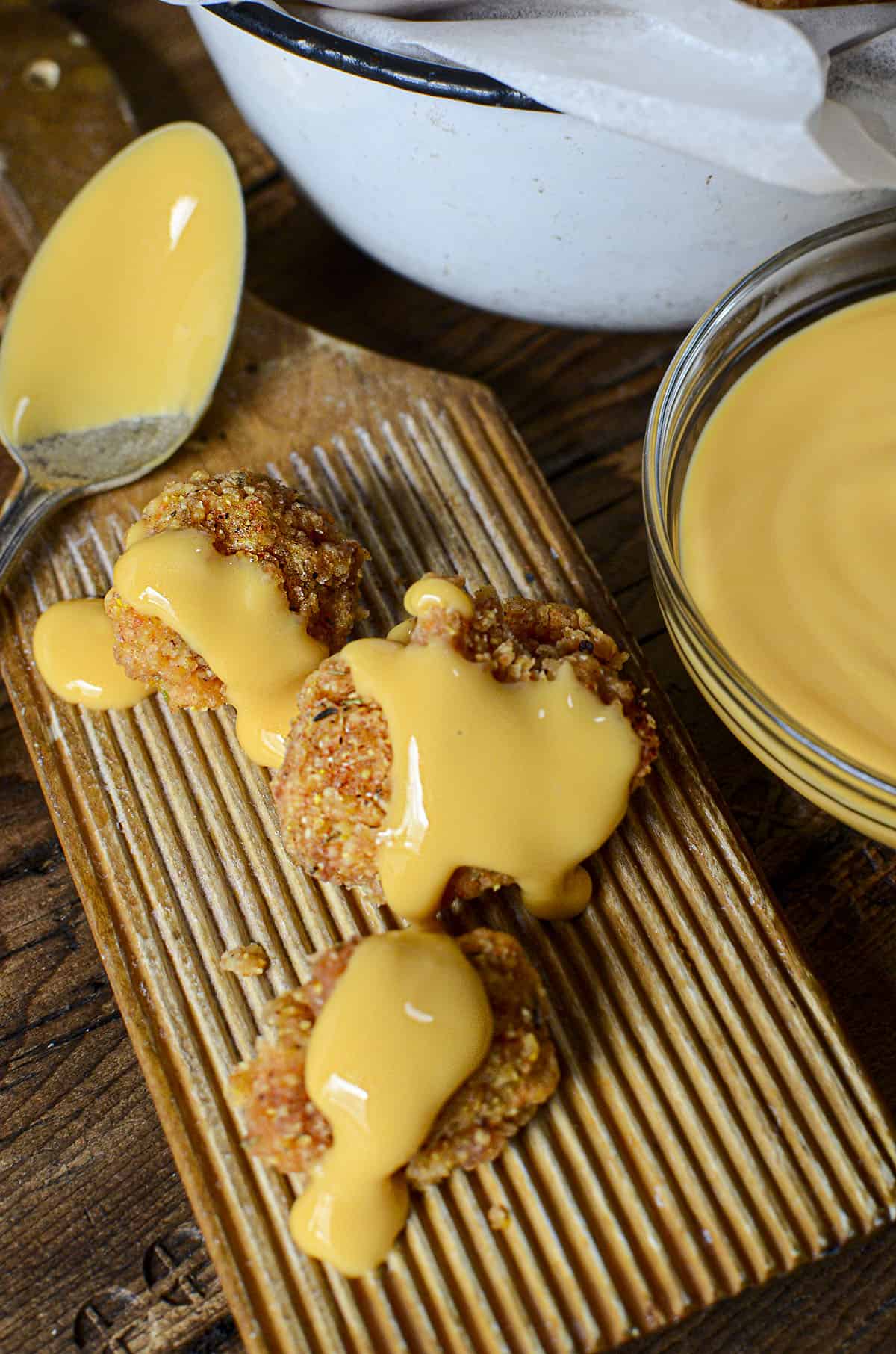 Popcorn bites on a wooden board with nacho cheese drizzled over top.