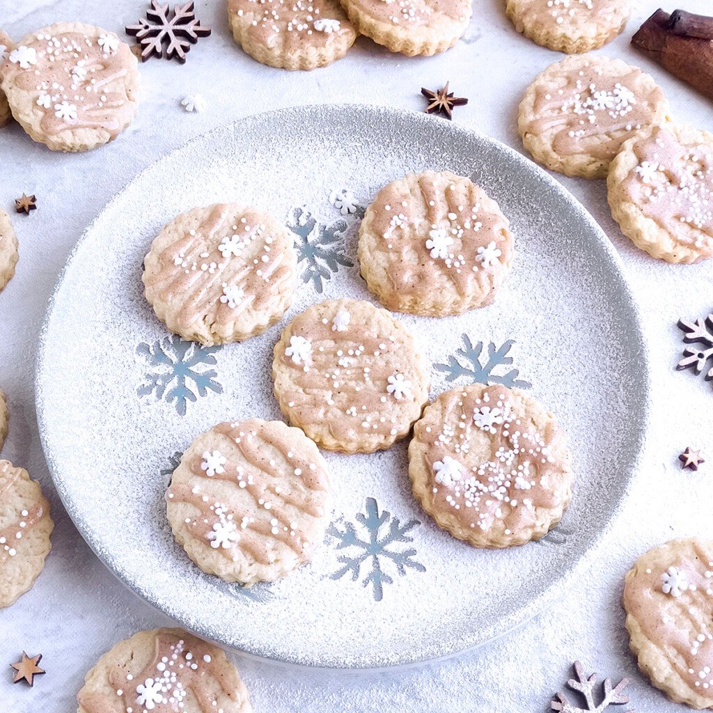 Five eggnog cookies sitting on a plate with other cookies around it.