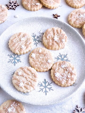 Five eggnog cookies sitting on a plate with other cookies around it.