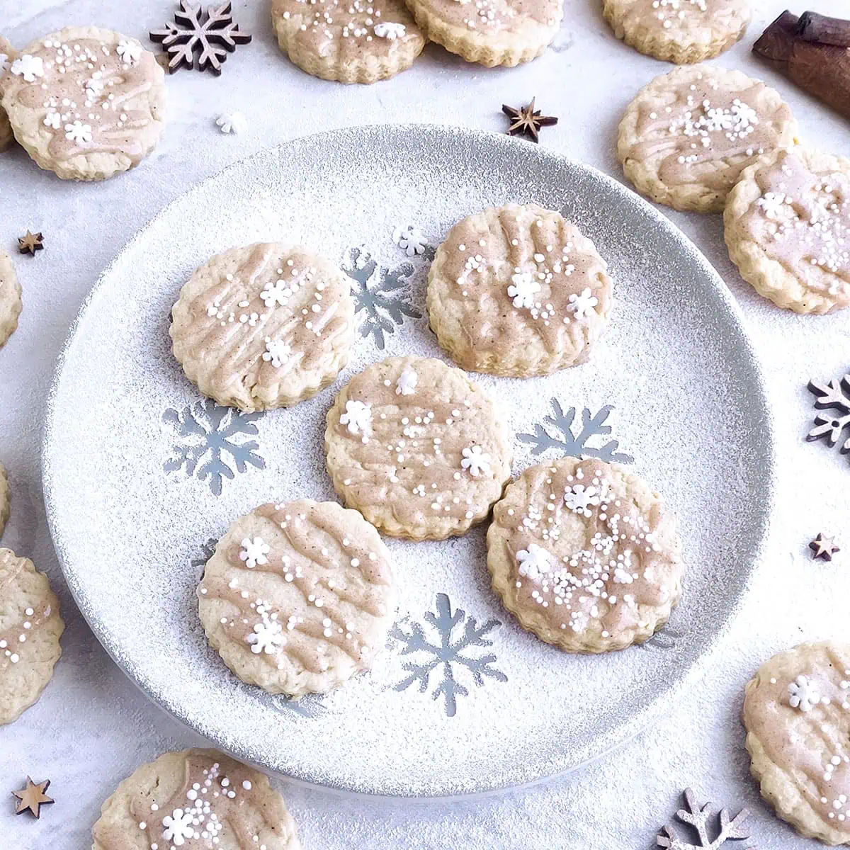 Five eggnog cookies sitting on a plate with other cookies around it.