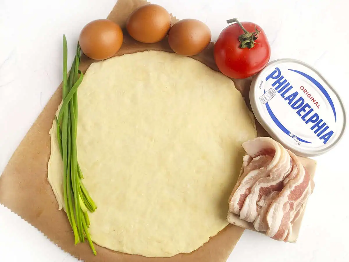 Ingredients for the breakfast galette. Pie crust, eggs, a tomato, cream cheese, and bacon. Green onion is optional.