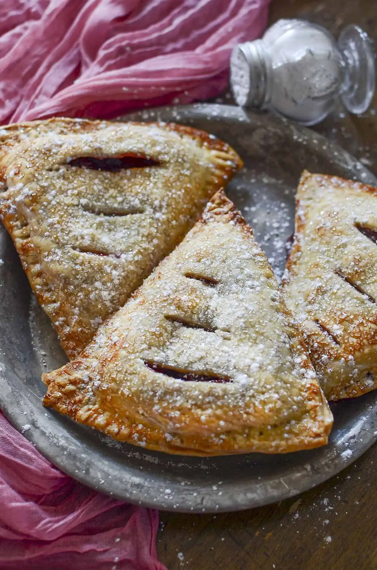 3 cherry hand pies on a tin plate.