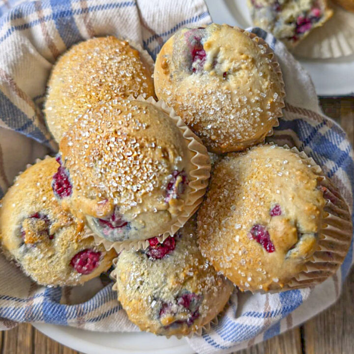 6 tart cherry muffins in a bowl with a blue and white checked tea towel underneath.