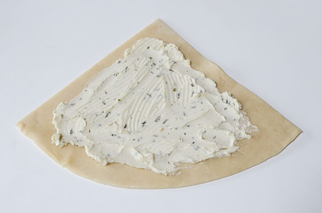 Cheese spread is spread over top one of the pastry sections.