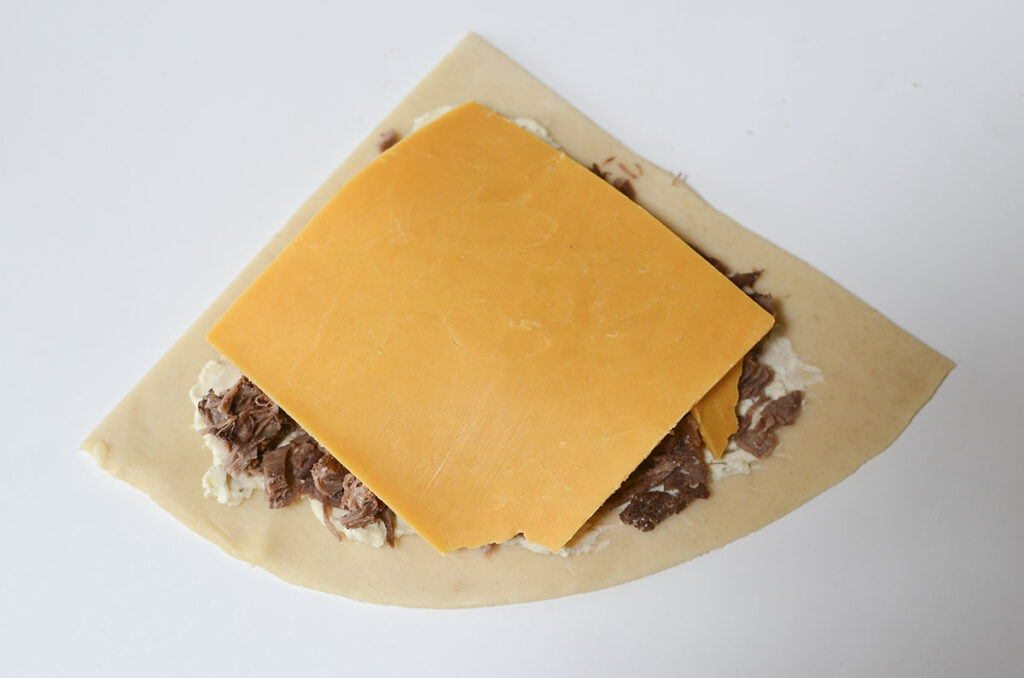 A slice of cheddar is placed on top of the beef.