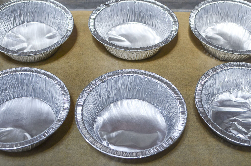 Foil ramekins on a parchment lined baking dish.