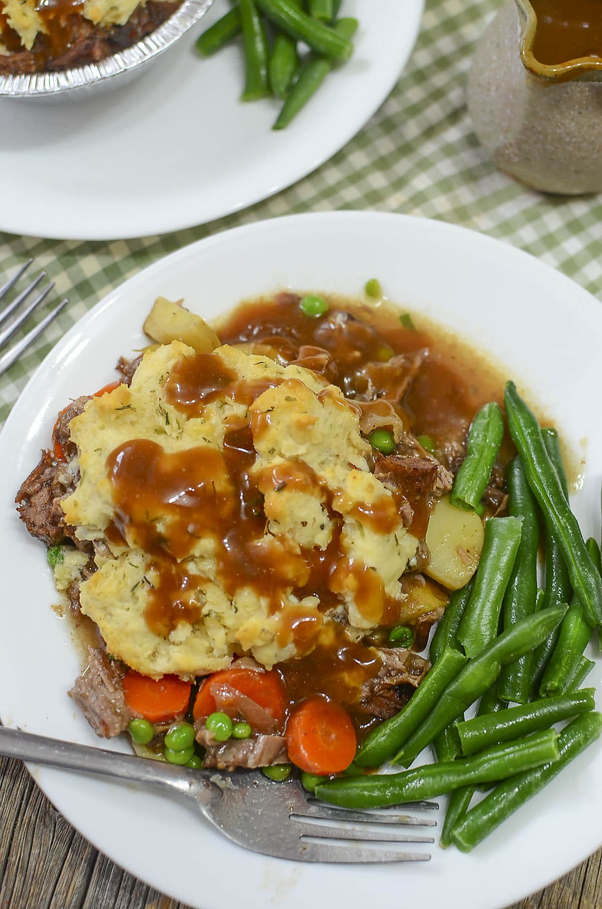 Beef pot pie for one on a plate with gravy.