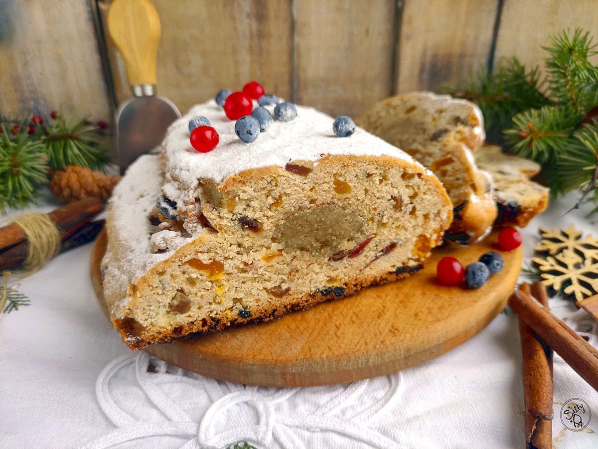 Holiday stollen bread with slices beside it on a wooden tray.