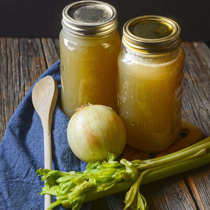 2 mason jars filled with soup stock, celery and onions in the front.