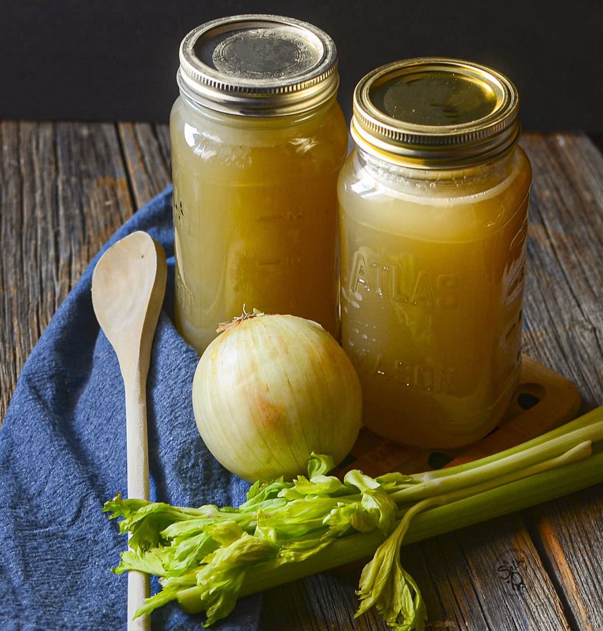 2 mason jars filled with soup stock, celery and onions in the front.