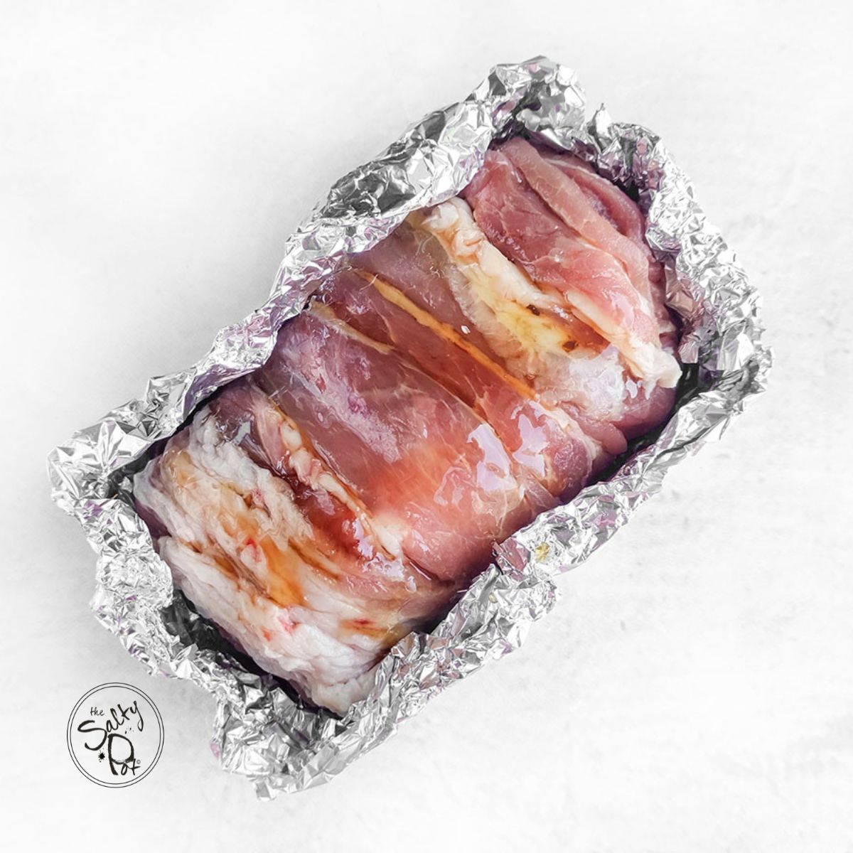Pork loin wrapped with bacon in foil