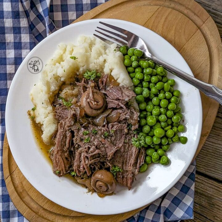 Dutch oven roast beef served with mash potato and peas in a white plate