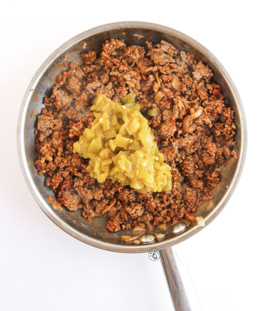 Seasoned taco beef mixture simmering with green chiles in skillet.