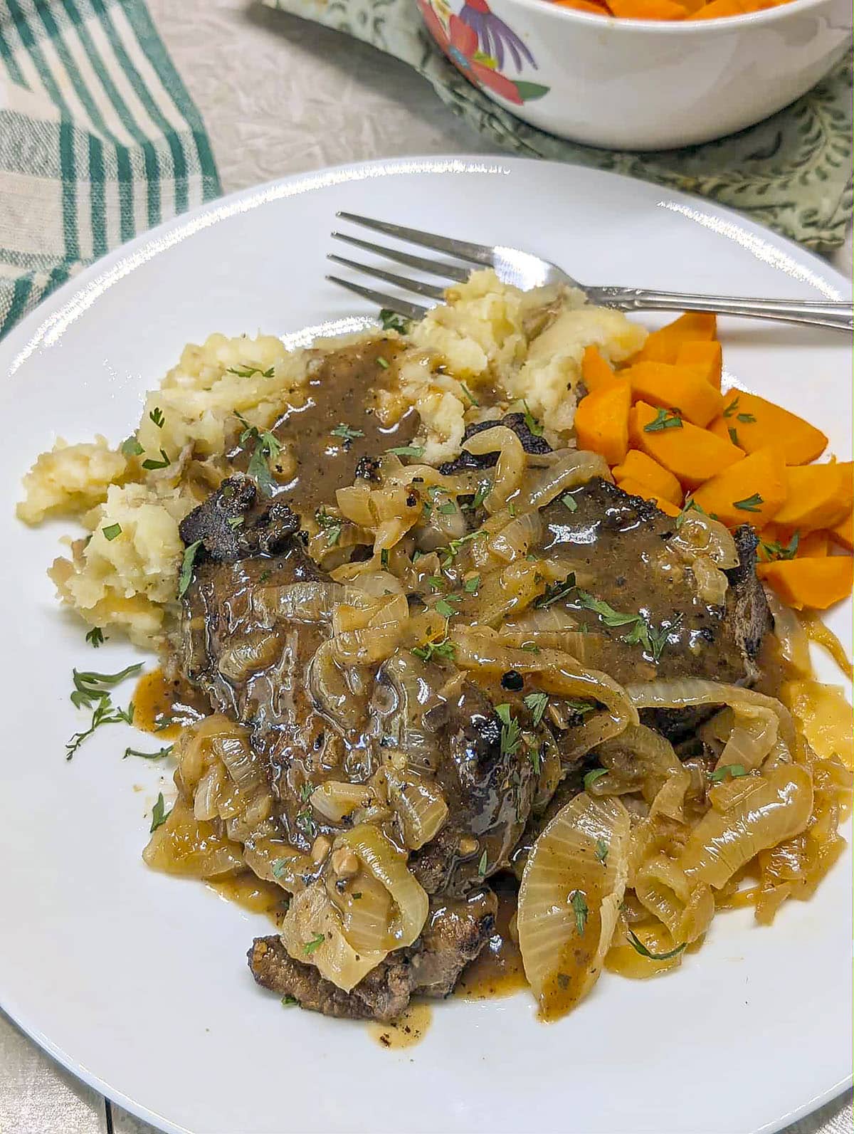 Liver with onions and carrots on a white plate.