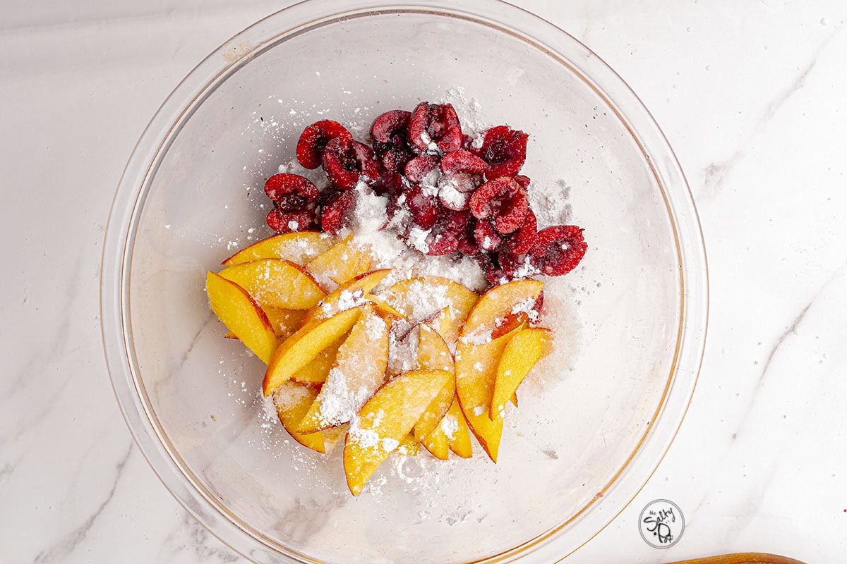 Fruit in a bowl (nectarines, cherries and raspberries) with flour sprinkled over top.