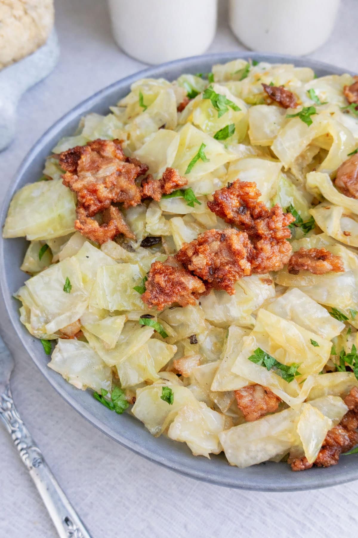 Air fryer cabbage and bacon on a blue plate with a fork on the left.