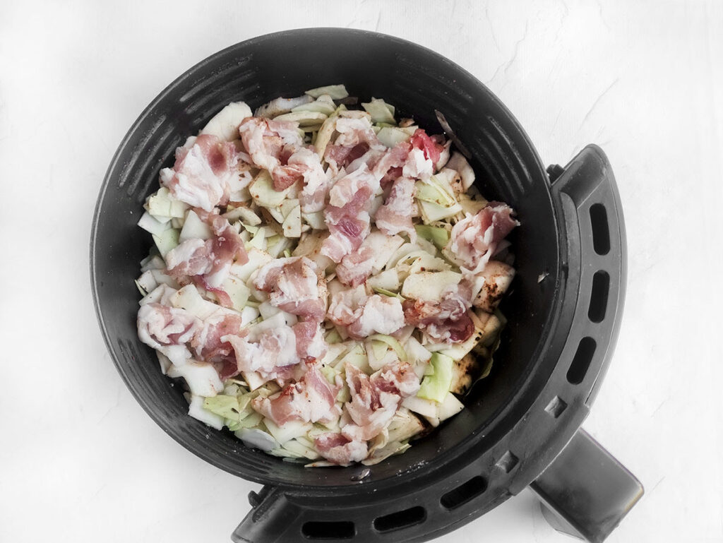 Chopped bacon on top of the cabbage in the air fryer.