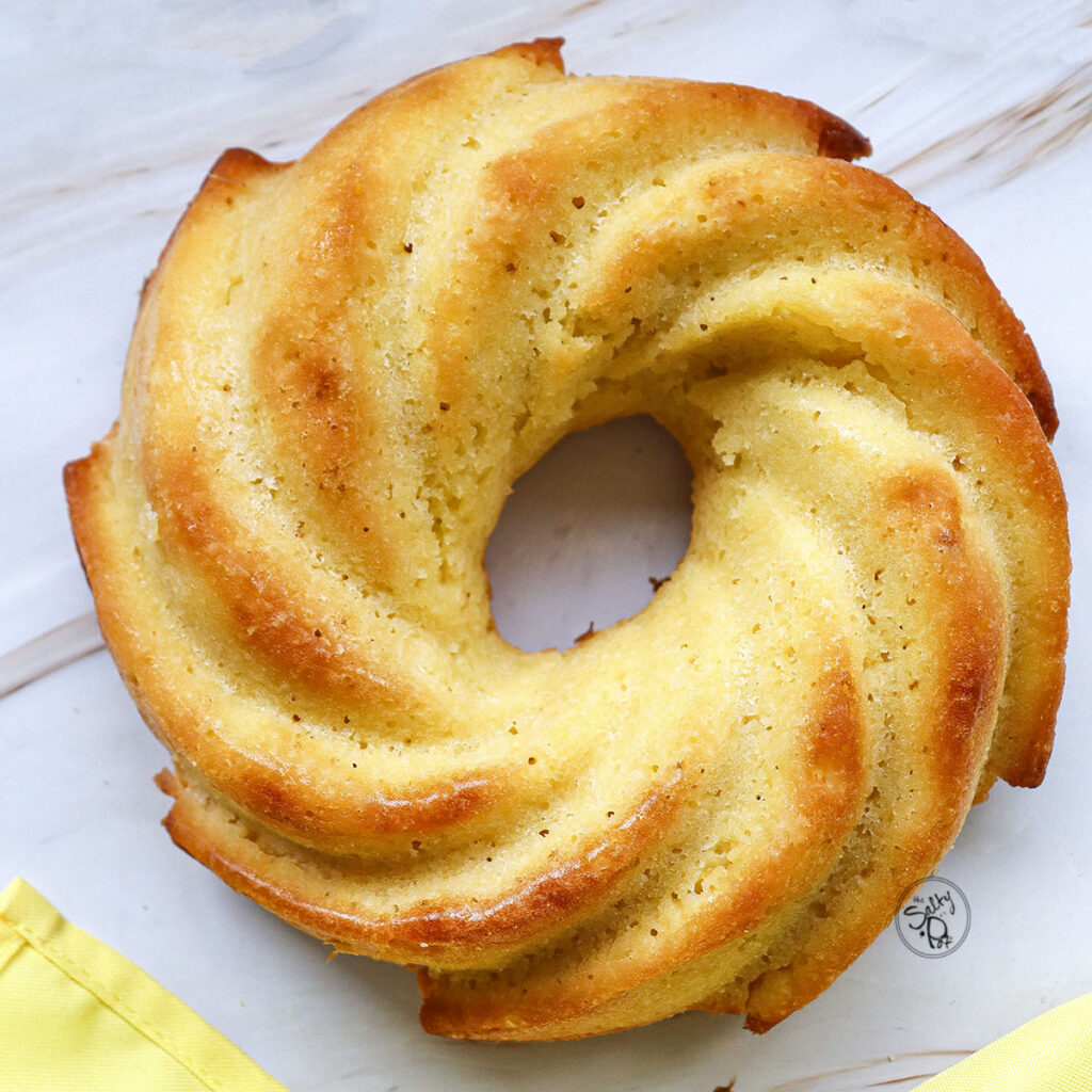 A top-down shot of the fully baked, golden-brown lemon bundt cake showing the intricate spiral design from the pan.