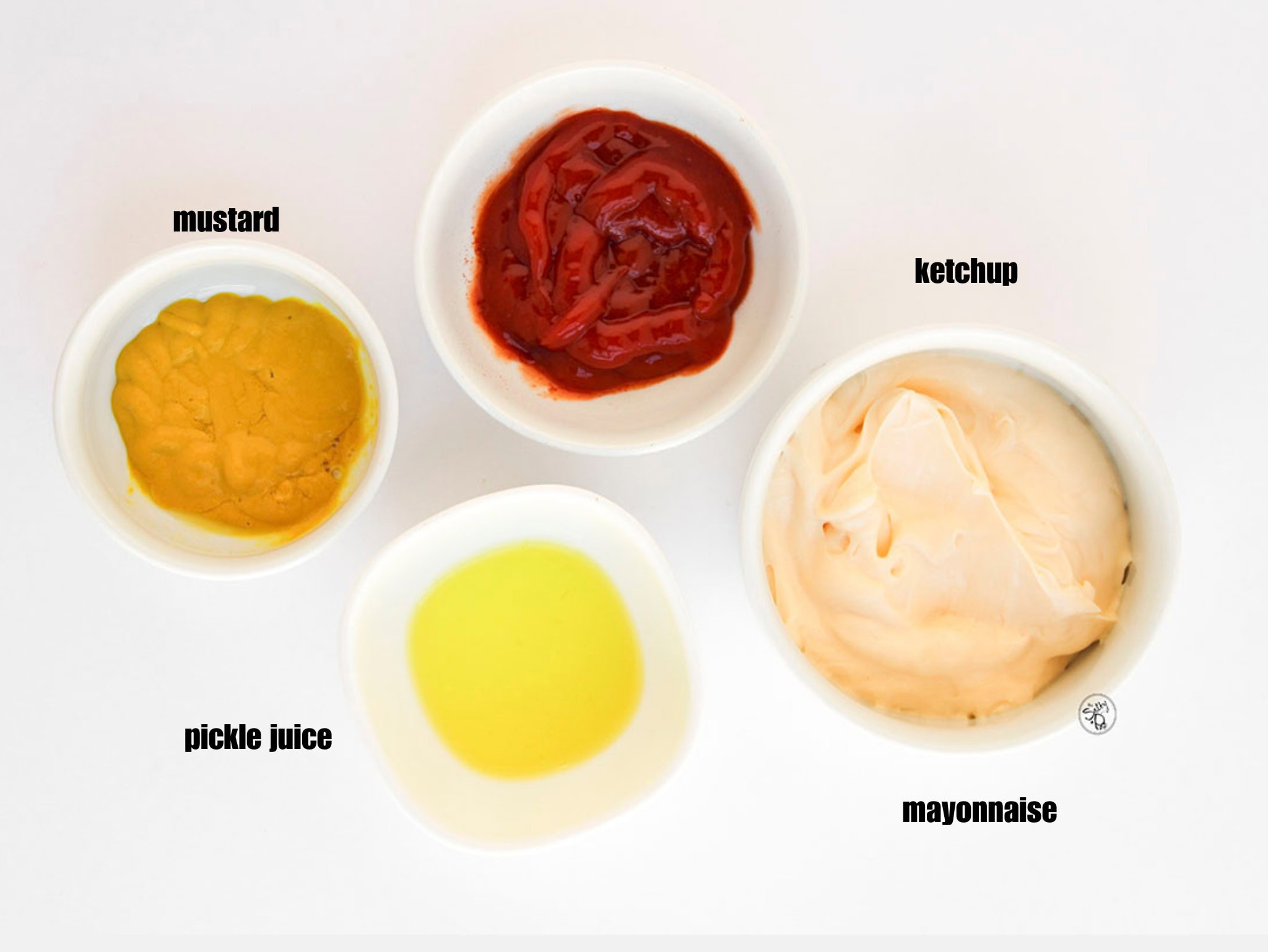 Four small white bowls containing the burger sauce components: mayonnaise, ketchup, yellow mustard, and clear pickle juice.