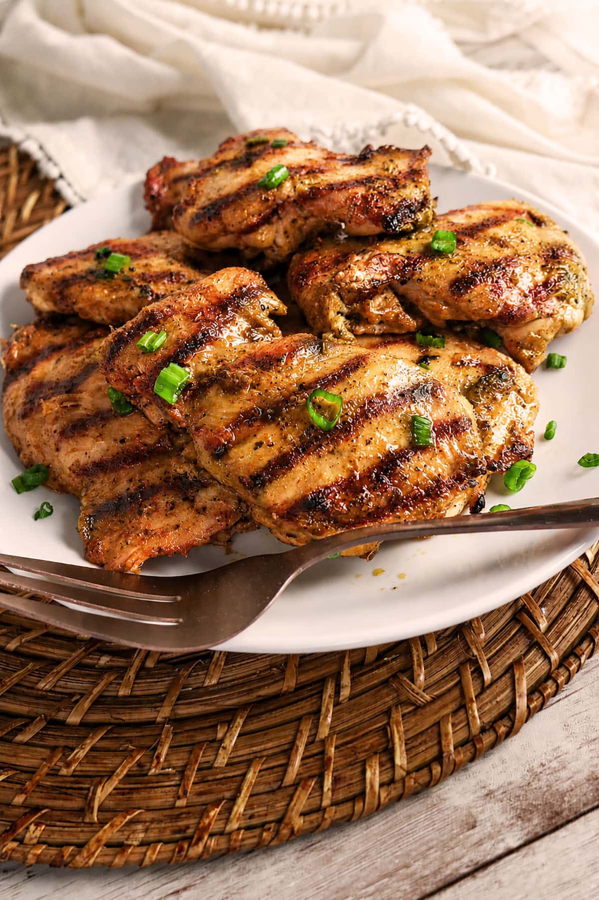 A platter of cooked chicken pieces with grill marks, garnished with green onions.