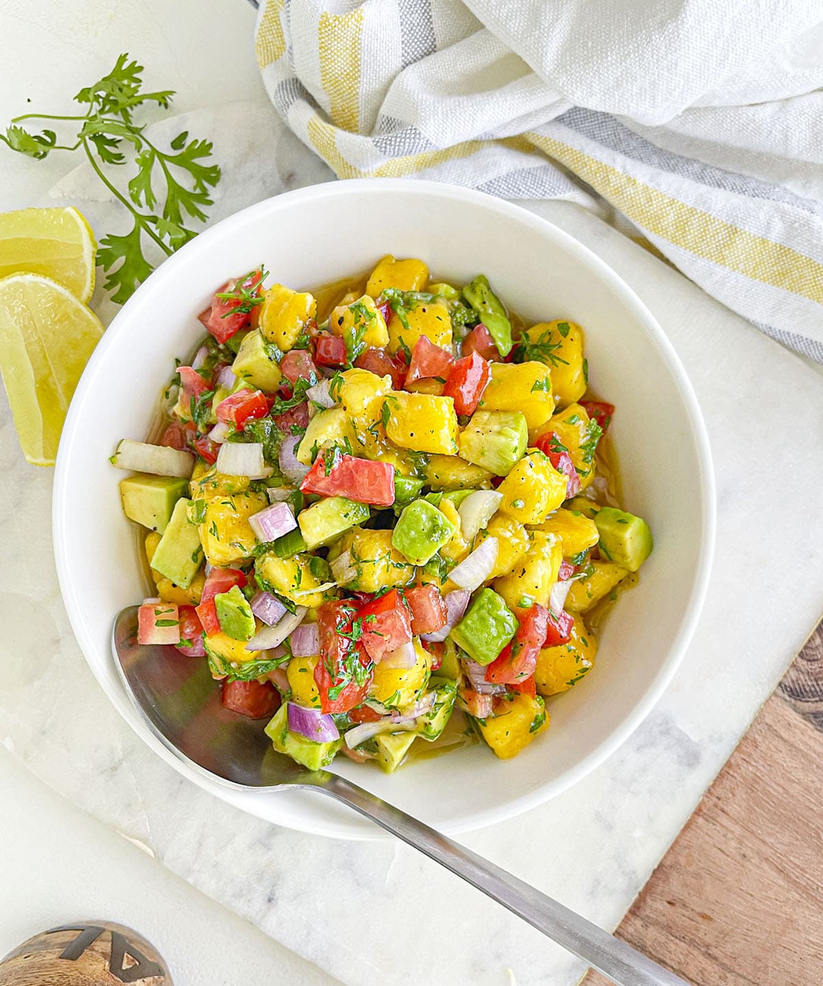 Mango avocado salsa in a white bowl with a spoon.