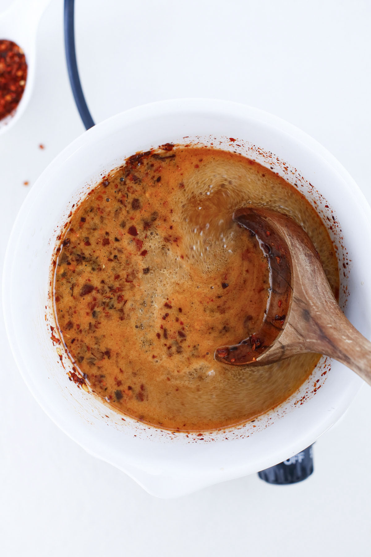 Infusing hot honey in a white bowl.