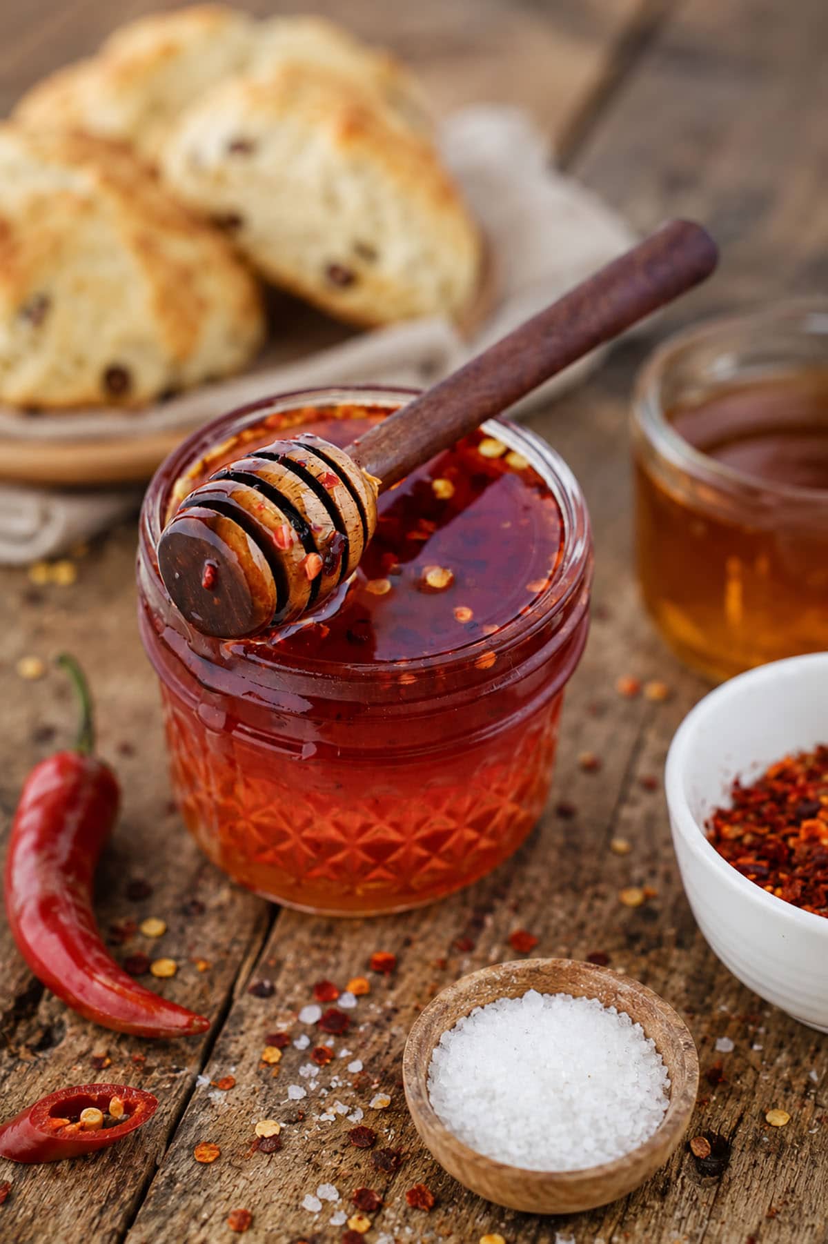 Hot honey in a pretty jar with spices and a honey stirrer laying across the top of the jar.
