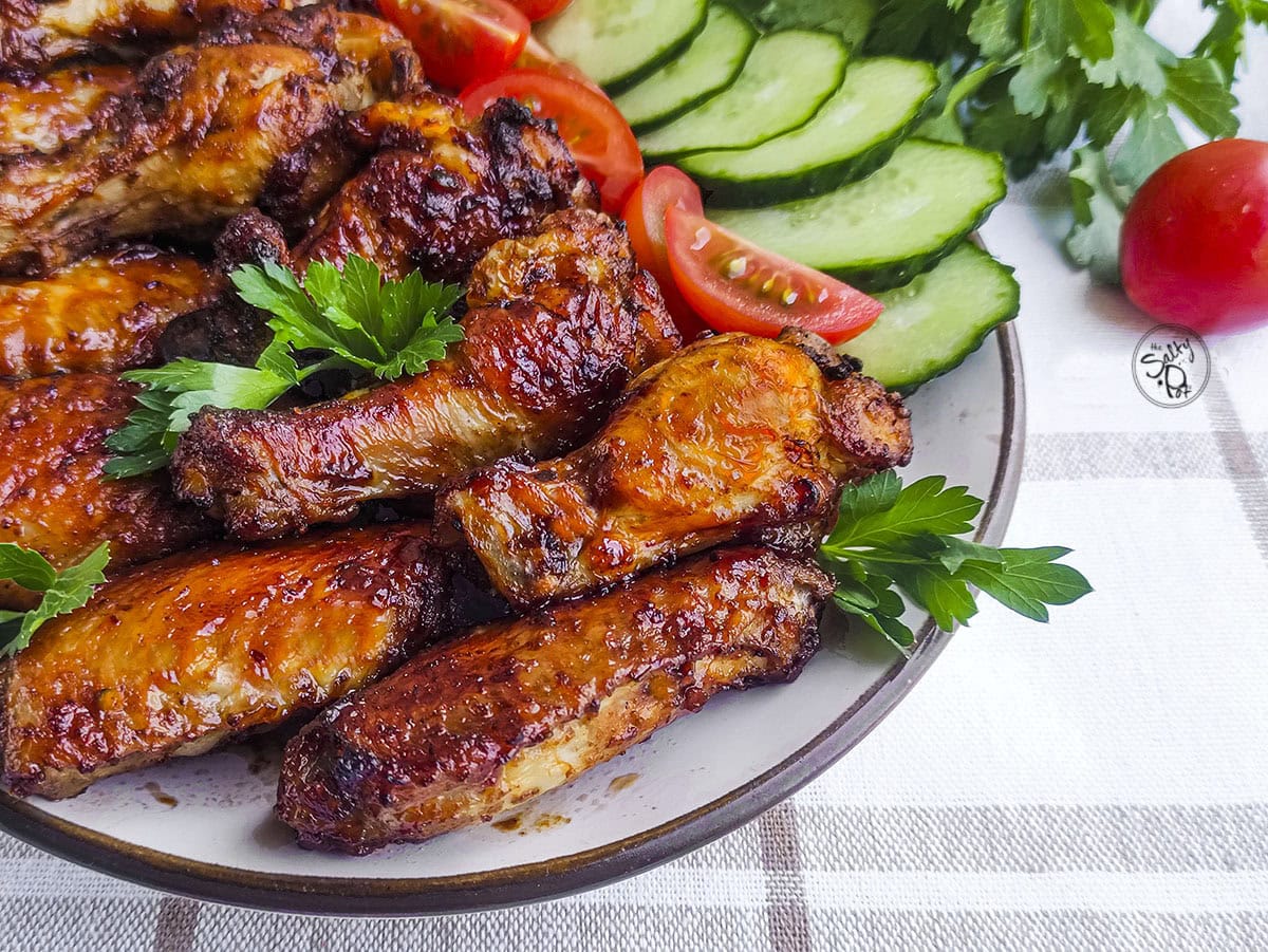 A close-up view of cooked air fryer chicken wings coated in sticky barbecue sauce on a serving platter.
