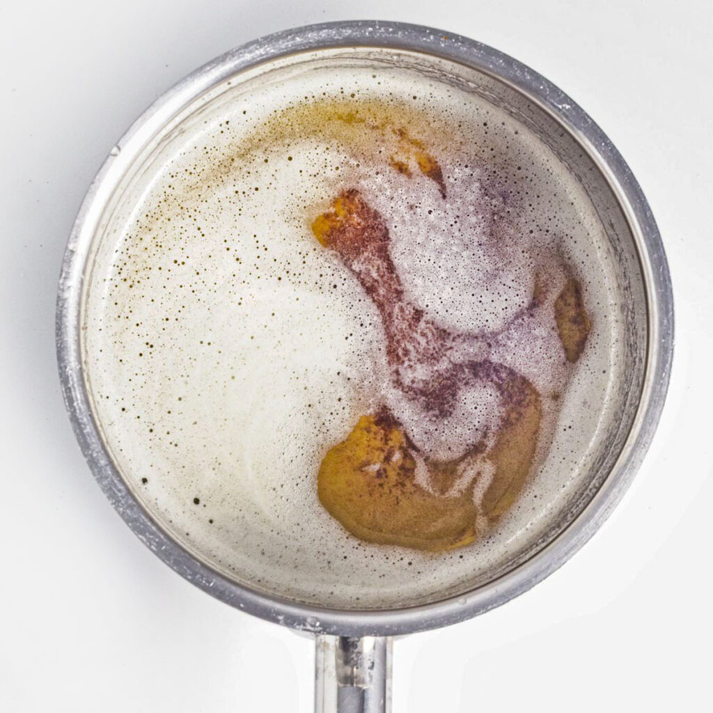 Melted butter simmering in a stainless steel saucepan.
