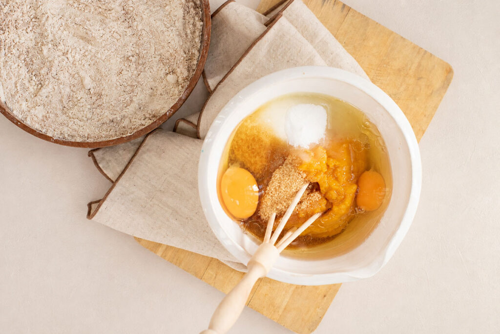 Mixing bowl filled with wet baking ingredients alongside a bowl of dry flour mixture