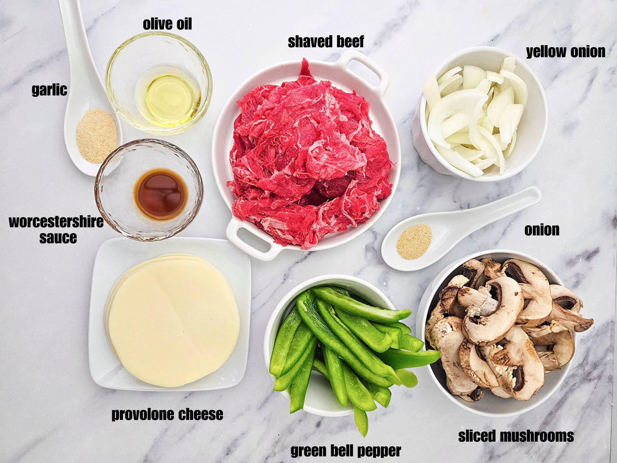 Raw meat, sliced vegetables, cheese, and seasonings arranged in small bowls.
