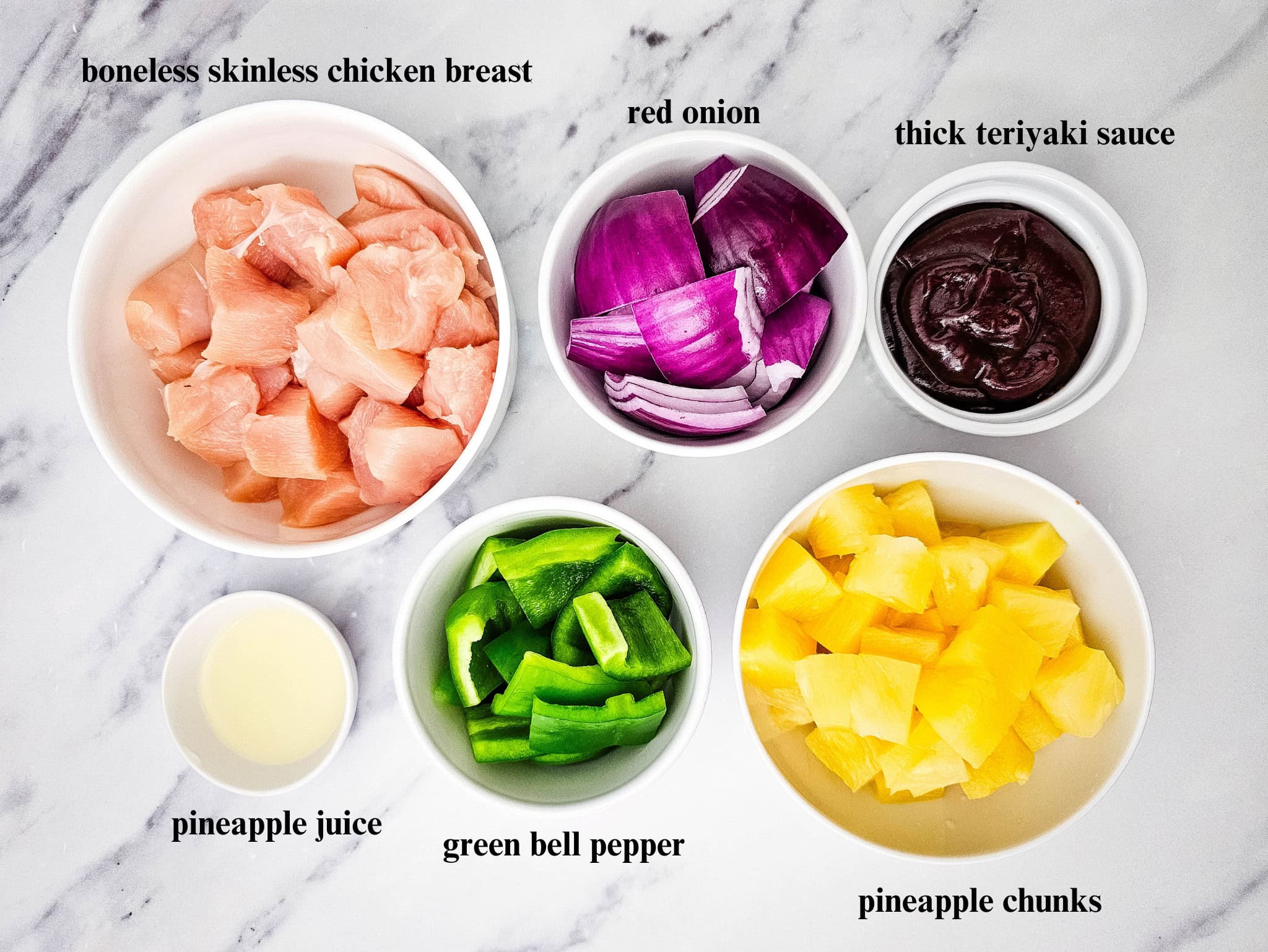 Top-down view of prepped ingredients in separate white bowls including chicken, pineapple, peppers, and red onion