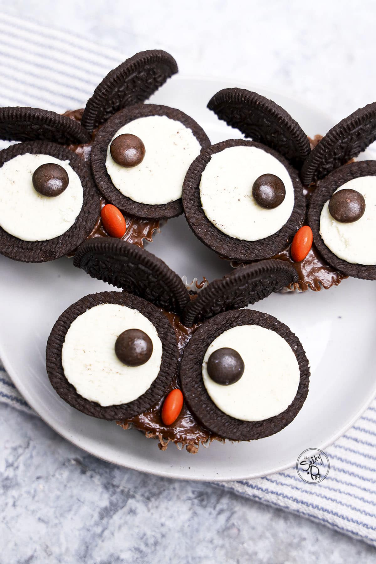 Plate of chocolate cupcakes decorated with sandwich cookies and candies to form owl faces