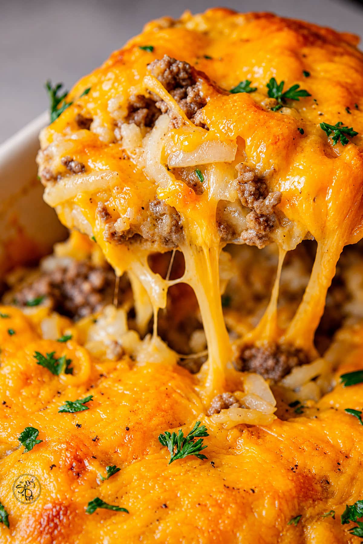 Hamburger hashbrown casserole with a piece being lifted out of the pan.