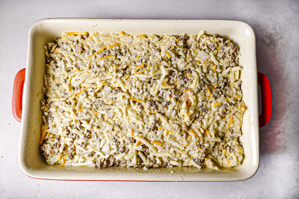 All the casserole ingredients in a red and white baking dish.