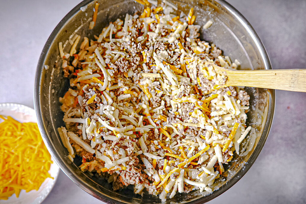 All the ingredients in a mixing bowl with some reserved cheese on the left for topping before baking.
