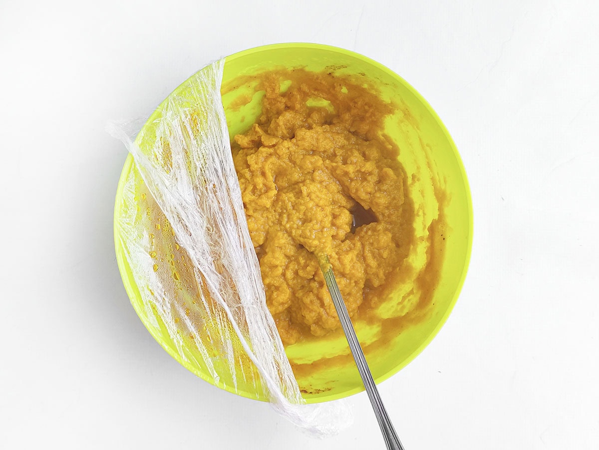 Bright green bowl containing spiced pumpkin filling covered partially with plastic wrap